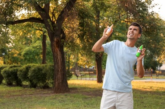 homem com repelentes para combater picada de mosquitos